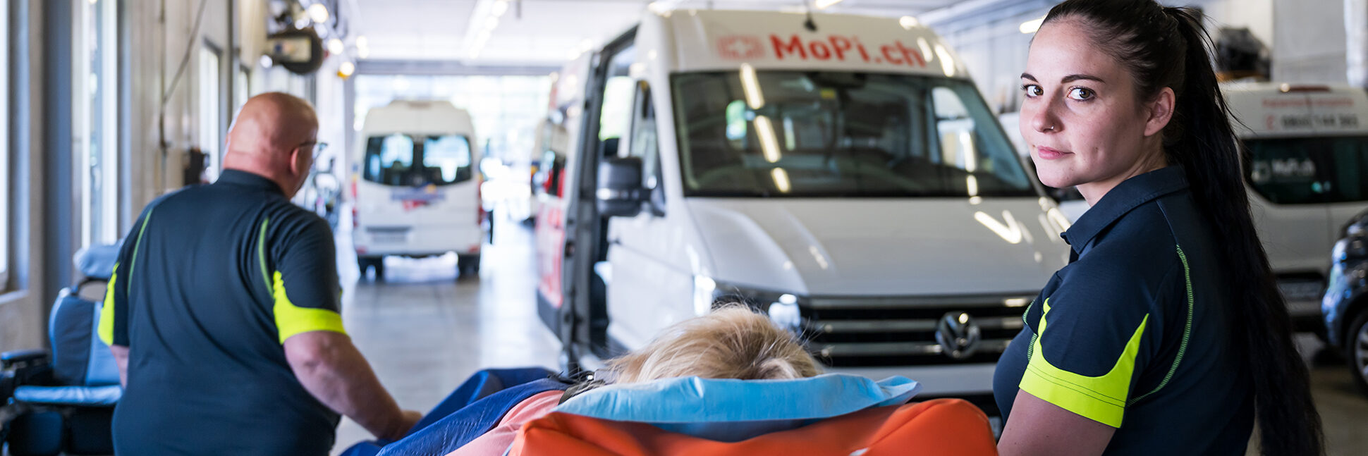A patient on a stretcher being loaded into the vehicle by two staff members